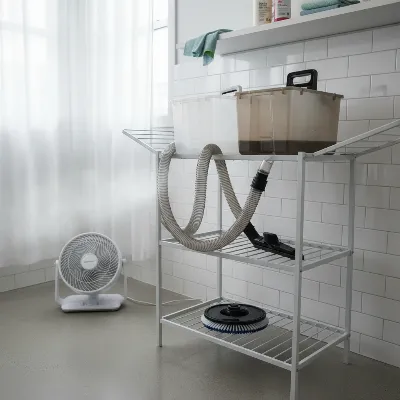Various portable carpet cleaner parts, including tanks and hoses, air-drying on a rack with a fan blowing towards them, illustrating the critical drying process for mold prevention. 