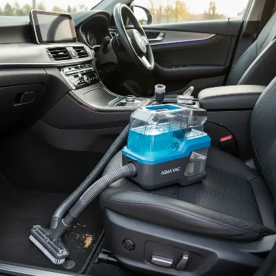 A portable carpet cleaner with its hose and various attachments laid out on a car seat, highlighting key features like hose length and different brush tools.